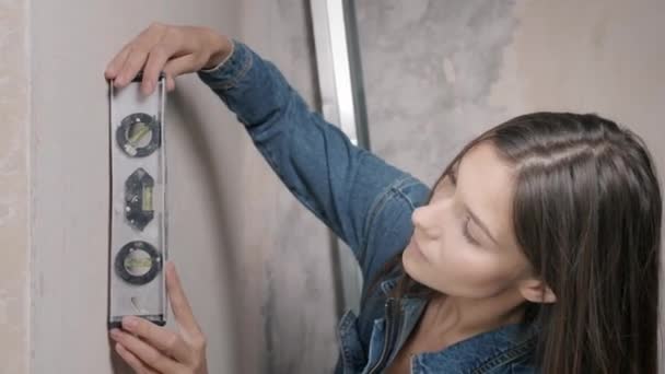 リノベーションアパート。美しい笑顔の女性がアパートで修理をしている。空の壁、自分の手で家を修復する. — ストック動画
