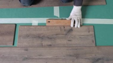 İşçi, laminatı daireye bırakıyor. Laminate apartmanın zemininde yatıyordu, üstat bir levha aldı ve yere koydu..