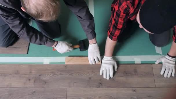 일꾼 들은 아파트에 매끈 한 바닥재를 놓는다. 아파트 수리, 바닥 깔개 — 비디오