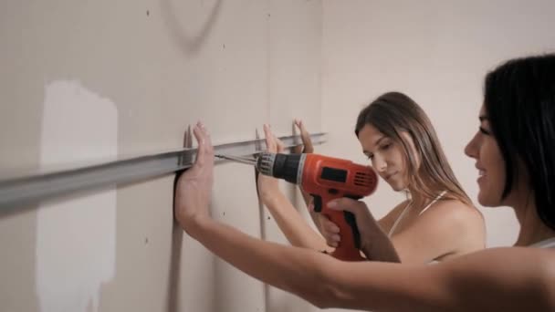 Młode kobiety dokonują napraw w mieszkaniu. Wierci coś w ścianie. — Wideo stockowe