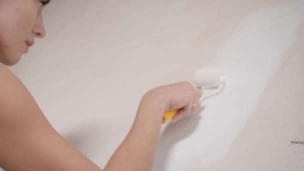 Genç ve güzel bir kadın dairede tamirat yapıyor. Kız evde kendi başına tamirat yapıyor duvarları boyuyor. — Stok video