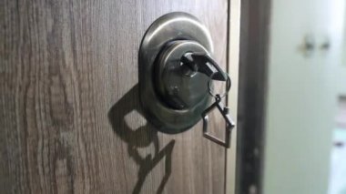 Bir adam kapıyı anahtarla açıyor.