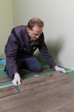 Efendi laminatı hazırlıyor. Adam zemini tamir ediyor.. 