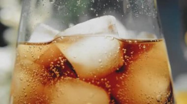 Karanlık bir arka planda buzlu soda dolu bir bardakta