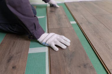 İşçi, laminatı daireye bırakıyor. Laminate apartmanın zemininde yatıyordu, üstat bir levha aldı ve yere koydu..