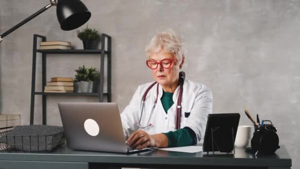 中年の女性医師がビデオ会議の患者と話をする。遠隔医療、オンライン患者相談 — ストック動画