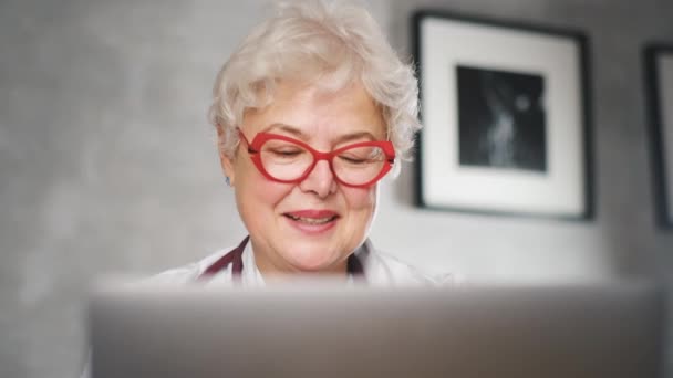 A middle-aged female doctor talks to a video conference patient. Telemedicine, online patient consultation — Stock Video