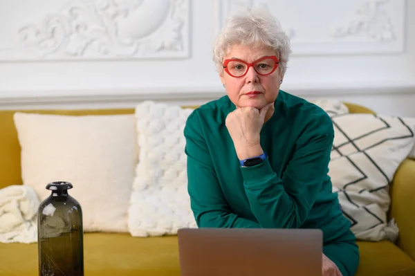 Старша зріла жінка дивиться бізнес-тренінги, онлайн-вебінар на портативному комп'ютері віддалена робота або соціальне дистанційне навчання з дому — стокове фото