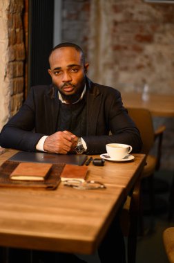 Afro-Amerikalı bir adam bir kafede dizüstü bilgisayarda çalışıyor. Ücretsiz çalışma programı, serbest çalışan