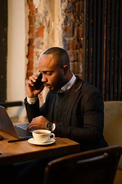 Um afro-americano está a trabalhar num portátil num café. Horário de trabalho gratuito, freelancer — Fotografia de Stock