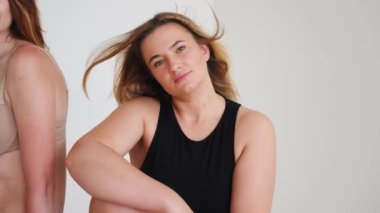 Arkadaşlık, güzellik, vücut pozitifliği ve insanların konsepti. İç çamaşırlarıyla gri arka plan üzerinde farklı kadınlar grubu.