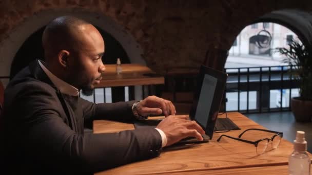 Afroamerikaner arbeitet an einem Laptop in einem Café. Freie Arbeit, freie Mitarbeiter — Stockvideo