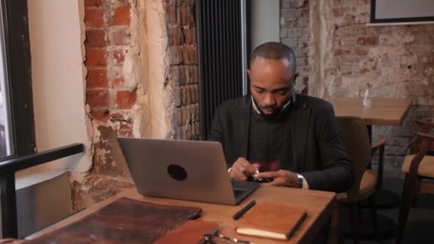 Afroamerikaner arbeitet an einem Laptop in einem Café. Freie Arbeit, freie Mitarbeiter — Stockvideo