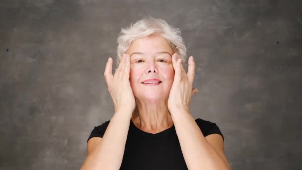 Feliz sonrisa atractiva mujer de mediana edad tocando la cara mirando a la cámara. Publicidad del concepto de procedimientos de spa de cuidado de la piel. Retrato de primer plano — Vídeos de Stock