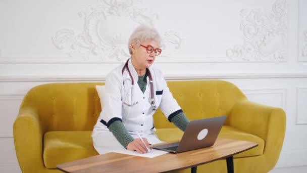 Médico femenino de mediana edad usando portátil, escribiendo notas con estetoscopio en la mesa. Concepto de salud. Médico médico escribiendo y tomando notas — Vídeo de stock