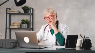 Orta yaşlı bir kadın doktor bir video konferans hastasıyla konuşuyor. Teletıp, online hasta danışmanlığı