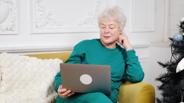 An adult woman with gray hair works at a laptop. video conference. Remote work — Wideo stockowe