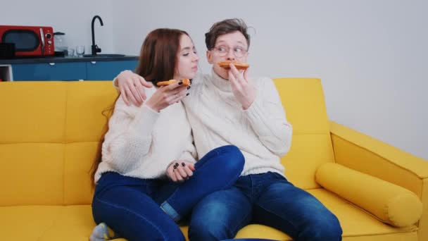 Een jong liefdevol stel brengt tijd samen thuis door, eet pizza en lacht — Stockvideo