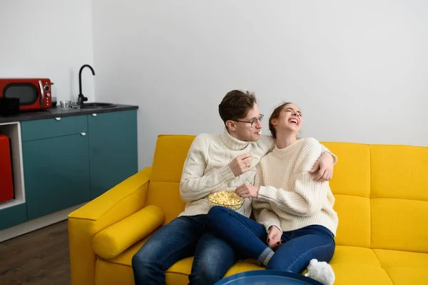 Um jovem casal bonito passar o tempo juntos em casa assistindo TV e rindo — Fotografia de Stock