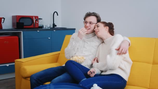 Молодая красивая пара проводит время вместе дома перед телевизором и смеется — стоковое видео