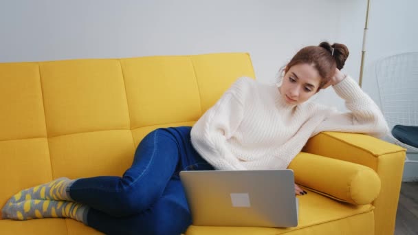 Uma jovem mulher está usando computador portátil para trabalho remoto ou estudando online — Vídeo de Stock