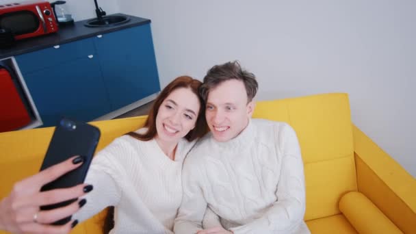 Positivo giovane coppia prendendo selfie mentre seduto sul divano a casa — Video Stock