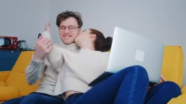 Evde dizüstü bilgisayar kullanan gülümseyen bir çift.