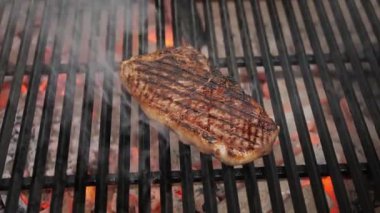 Kızarmış etli biftek, baharat ve otlarla birlikte, yanan kömürlerin içinde, bbq ızgarası, alevler ve duman. Barbekü ızgarası