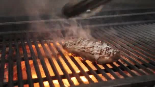 Roasting juicy meat steak with spices and herbs in burning charcoals fire on bbq grid, flames and smoke. Barbecue grill — Stock Video