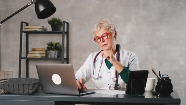 El médico de edad de las mujeres lleva a cabo una consulta en línea con la paciente. telemedicina — Vídeos de Stock