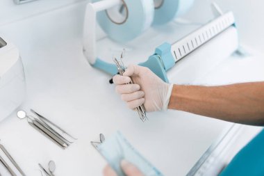 Diş hekimi asistanı plastik sterilizasyon torbalarında dişçi ekipmanlarını sterilize edip paketliyor