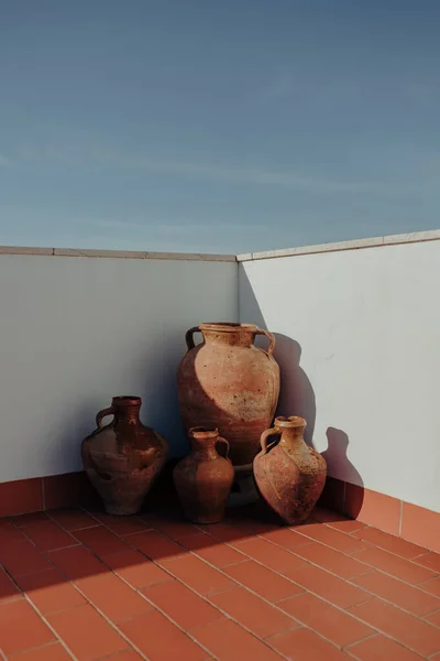 Old broken large mud vessels on the floor outside in a rooftop corner with harsh light