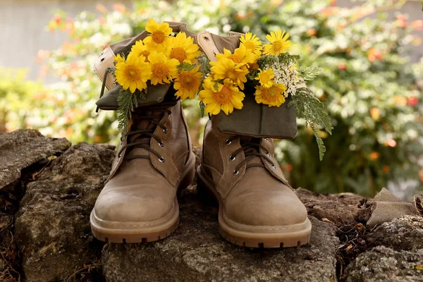 石の上に美しい黄色の花を持つブーツ屋外 — ストック写真