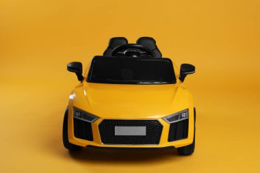 Sarı arka planda çocuğun elektrikli oyuncak arabası.