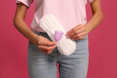 Aybaşı fincanı ve parlak pembe arkaplanı olan genç bir kadın, yakın plan.