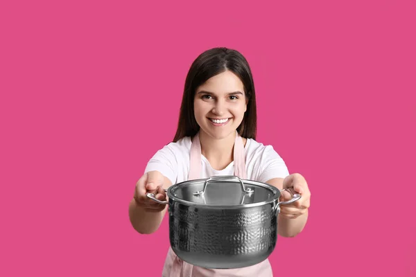 幸せな若いです女性とともに調理鍋でピンクの背景 — ストック写真