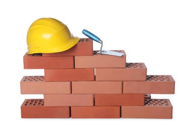 Many red bricks, hard hat and trowel on white background clipart