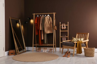 Modern soyunma odasının içinde giysi askısı, ayna ve rahat koltuk var.