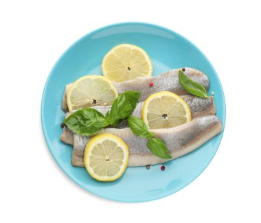 Lezzetli salamura fileto, fesleğen, limon dilimleri ve beyaz üzerine izole edilmiş karabiber soslu mavi tabak.