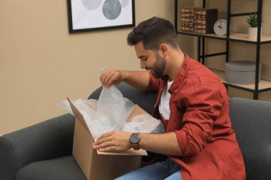 Evdeki paketleri açan adam. İnternetten alışveriş