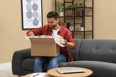 Evdeki paketleri açan adam. İnternetten alışveriş