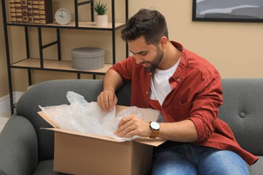 Man unpacking parcel at home. Online shopping clipart