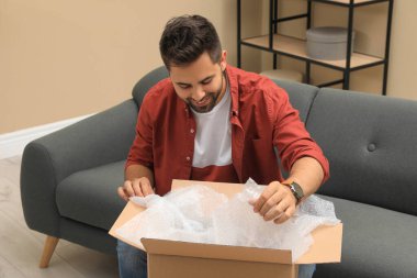 Evdeki paketleri açan adam. İnternetten alışveriş