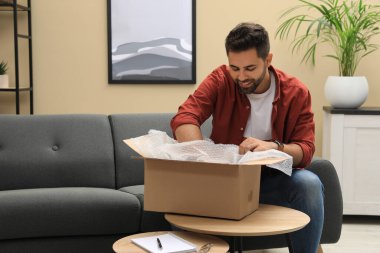 Evdeki paketleri açan adam. İnternetten alışveriş