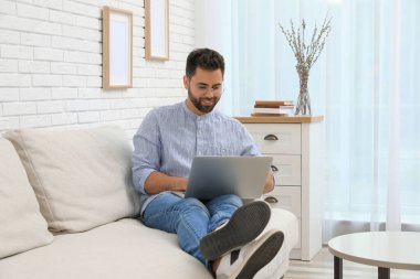 Evde online alışveriş için dizüstü bilgisayar kullanan bir adam