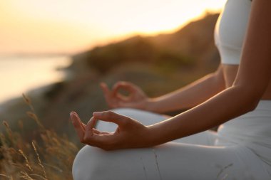 Gün batımında meditasyon yapan kadın, yakın çekim görüntüsü.