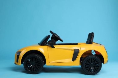 Açık mavi arka planda çocuğun elektrikli oyuncak arabası