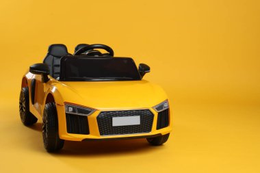 Sarı arka planda çocuğun elektrikli oyuncak arabası. Metin için boşluk