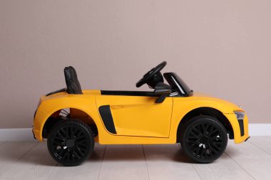 Bej duvarın yanındaki çocuk elektrikli oyuncak arabası.