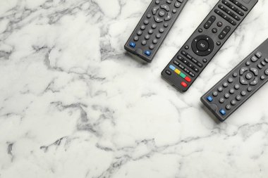 Modern TV uzaktan kumandaları beyaz mermer masada, düz yerde. Metin için boşluk